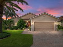 Beautiful home exterior with lush landscaping, brick driveway, and a two-car garage at sunset at 4327 Gullane Dr, Lake Wales, FL 33859