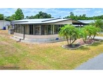 Charming home featuring a screened lanai, well-manicured lawn, and beautiful landscaping with palm trees at 6470 Peppertree Ne Path, Winter Haven, FL 33881