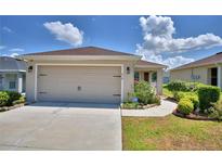 This home features an attached two-car garage with manicured flower beds, lawn and landscape along the driveway at 710 Persian Dr, Haines City, FL 33844