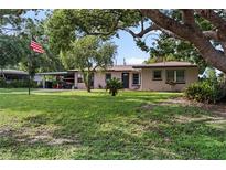 Charming single-story home with a well-manicured lawn, mature trees, and a covered parking area at 105 Leslie Ave, Winter Haven, FL 33880