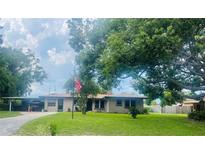 Charming single-story home with a lush green lawn, mature trees, and an American flag proudly displayed at 105 Leslie Ave, Winter Haven, FL 33880