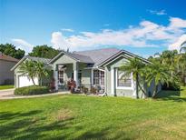 Landscaped front yard of a single-story home with palm trees and well-maintained green grass at 123 Evergreen Dr, Auburndale, FL 33823
