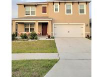 Charming two-story home featuring a well-maintained lawn, covered front porch, and attached two-car garage at 1378 Fox Squirrel Dr, Davenport, FL 33897
