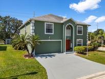 Charming two-story home with green exterior, white trim, neat lawn, and freshly paved driveway at 1800 Emily Dr, Winter Haven, FL 33884