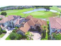 Stunning aerial view of a tile roof home overlooking a golf course and lake, featuring solar panels at 2340 Pinehurst Ct, Davenport, FL 33837