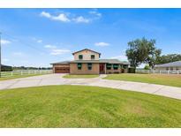 Charming two-story home with brick facade, lush lawn, circular driveway, and green awnings provides curb appeal at 2731 State Road 557, Lake Alfred, FL 33850