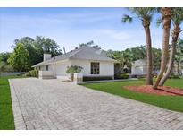 Charming one-story home with a paved driveway, lush lawn, and mature palm trees at 2987 Plantation Rd, Winter Haven, FL 33884