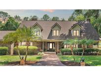 Charming brick home featuring a manicured lawn, complemented by lush palm trees and a welcoming brick pathway at 418 North Rd, Lakeland, FL 33809