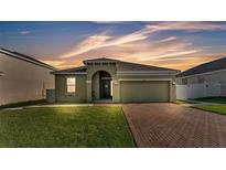 Inviting single-story home with a well-manicured lawn and a brick-paved driveway at 428 Aragosa Dr, Davenport, FL 33837