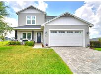 Charming two-story home with a well-manicured lawn and inviting covered front porch with seating at 445 Waterfern Trail Dr, Auburndale, FL 33823