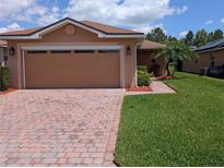 Charming home features a brick driveway, two-car garage, and well-maintained landscaping at 4488 Turnberry Ln, Lake Wales, FL 33859