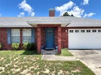 Charming brick home with a blue front door, shutters, and a well-manicured lawn under a sunny sky at 504 W 7Th St, Frostproof, FL 33843