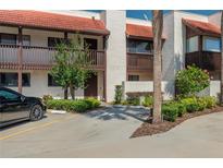 Condo exterior featuring a red tile roof, covered balcony, and well-maintained landscaping with ample parking at 5102 Village Ct # E-2, Lake Wales, FL 33898