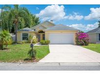 Inviting one-story home with a manicured lawn, lush landscaping, and a two-car garage at 630 Heather Glen Loop, Winter Haven, FL 33884