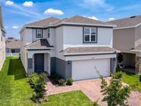 Beautiful two-story home featuring a well-manicured lawn, brick driveway, and attached two-car garage at 912 Scrub Oak Hammock Rd, Davenport, FL 33837