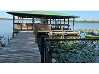 A spacious dock with a green roof and Jet Ski is an amazing feature for lake access and recreation at 9402 Cat Track Trl, Lake Wales, FL 33898