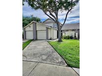 Charming two-story home with a spacious driveway, lush lawn, and mature trees providing shade at 12241 Augusta Woods Cir, Orlando, FL 32824