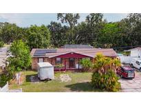 Charming single-story brick home featuring solar panels, a red trim, and mature landscaping at 2213 W Pilaklakaha Ave, Auburndale, FL 33823