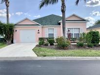 Charming pink single-story home featuring a well-manicured lawn and tropical landscaping at 263 Reserve Dr, Davenport, FL 33896