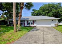 Charming single-story home with a well-manicured lawn, a two-car garage, and mature landscaping at 2909 Pine Tree Dr, Edgewater, FL 32141