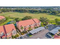 Aerial view of condo building showcasing lush landscaping, red tile roof, and assigned covered parking at 351 Enclave Dr # 94, Lakeland, FL 33803
