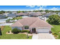 Well-maintained single-Gathering home featuring lush landscaping, a two-car garage, and a charming, light-colored exterior at 413 Ruby Lake Pl, Winter Haven, FL 33884