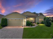 Charming one-story home featuring well-manicured lawn, brick driveway, and a cozy, inviting entrance at twilight at 4356 Ashton Club Dr, Lake Wales, FL 33859