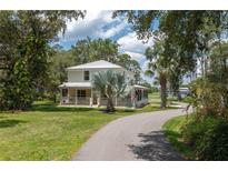 Charming two-story home with a metal roof, inviting front porch, and lush landscaping at 4949 Lake Kotsa Dr, Lake Wales, FL 33898