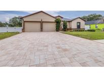 Inviting home featuring a two-car garage, neutral paint, stone accents, and a long, patterned paver driveway at 607 S 16Th St, Haines City, FL 33844