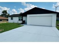 Charming home featuring a freshly painted exterior, a two-car garage, and a well-maintained front yard under a blue sky at 655 E Sanford St, Lake Alfred, FL 33850