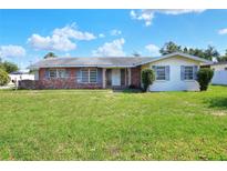 Charming single-story home with a brick facade and well-maintained front lawn and a lush green lawn at 961 Piedmont Se Dr, Winter Haven, FL 33880