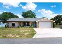 Charming single-story home with stone accents, a well-manicured lawn, and an attached two-car garage at 1334 Highland Park S Dr, Lake Wales, FL 33898