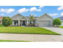 Charming single-story home with a well-manicured lawn, cozy front porch, and attached two-car garage at 204 Walkers Point Dr, Auburndale, FL 33823