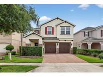 Charming two-story home featuring a brick driveway, well-manicured lawn, and red shutters at 2612 San Simeon Way, Kissimmee, FL 34741