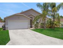 Charming single-story home featuring a two-car garage, a concrete driveway and well-maintained lawn with mature palms at 362 Lake Daisy Cir, Winter Haven, FL 33884