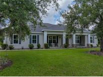 Inviting home exterior with a large front lawn and a covered porch with rocking chairs at 3985 Mammoth Grove Rd, Lake Wales, FL 33898
