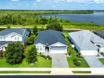 A charming single-story home with a manicured lawn and a view of the lake in the background at 505 Adams View Ln, Auburndale, FL 33823