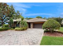 Charming brick home with a tile roof and lush landscaping on a beautiful, sunny day at 105 Woden Way, Winter Haven, FL 33884