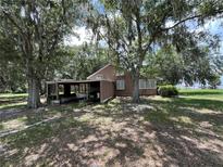 Charming home exterior featuring a covered carport and nestled under the shade of mature trees at 1805 S Lake Reedy Blvd, Frostproof, FL 33843