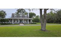 Charming home with lush green lawn, mature trees, and welcoming front porch at 1976 Holy Cow Rd, Polk City, FL 33868