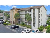 Exterior view of condo building with stone accents, balconies, well maintained landscaping and ample parking at 2037 San Marcos Se Dr # 443, Winter Haven, FL 33880
