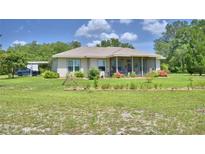 A single story ranch-style home with beige siding, a screened porch, and a well-manicured lawn at 2252 Fox Run Rd, Lake Wales, FL 33898