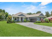 Beautiful gray single-story home with a well-manicured lawn and gray brick driveway at 2988 Sequoyah Dr, Haines City, FL 33844
