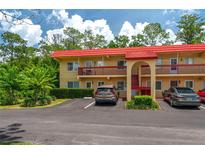 Charming condo building with red tile roof and mature landscaping near the parking lot at 400 El Camino Dr # 201, Winter Haven, FL 33884