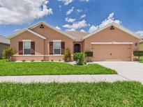 Single-story home featuring a well-manicured lawn, neutral color scheme, and attached two-car garage at 5751 Lakeside Landings Blvd, Winter Haven, FL 33881