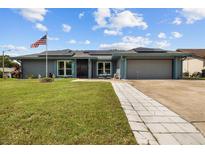 Charming single-story home featuring a lush lawn, solar panels, and an inviting walkway at 704 Butternut Pl, Lakeland, FL 33813