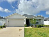 Charming single-story home features a manicured lawn, inviting curb appeal, and a neutral color palette at 737 Daphne Dr, Polk City, FL 33868