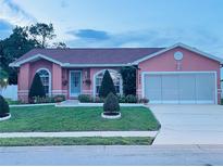 Charming single-story home featuring a well-manicured lawn, lovely landscaping, and a two-car garage at 1366 Merrimack Pl, Davenport, FL 33837