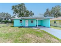 Charming turquoise home featuring a carport and well-maintained front yard and minimalist landscaping at 2125 Hillcrest Rd, Auburndale, FL 33823