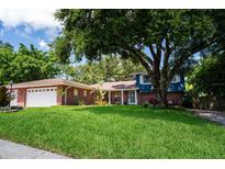 Charming brick home featuring a lush green lawn and mature trees offering plenty of shade at 237 Manatee Rd, Winter Haven, FL 33884